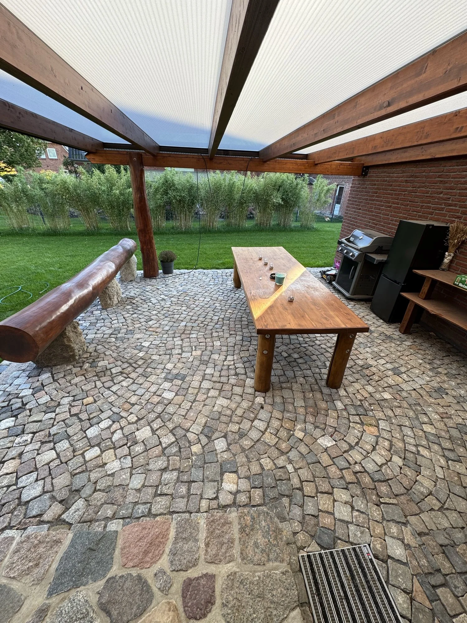 Überdachter Sitzplatz mit Natursteinpflaster und Holztisch