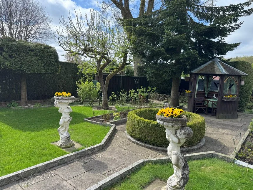 Gepflegter Garten mit Figur, Rasenfläche und eingefassten Beeten