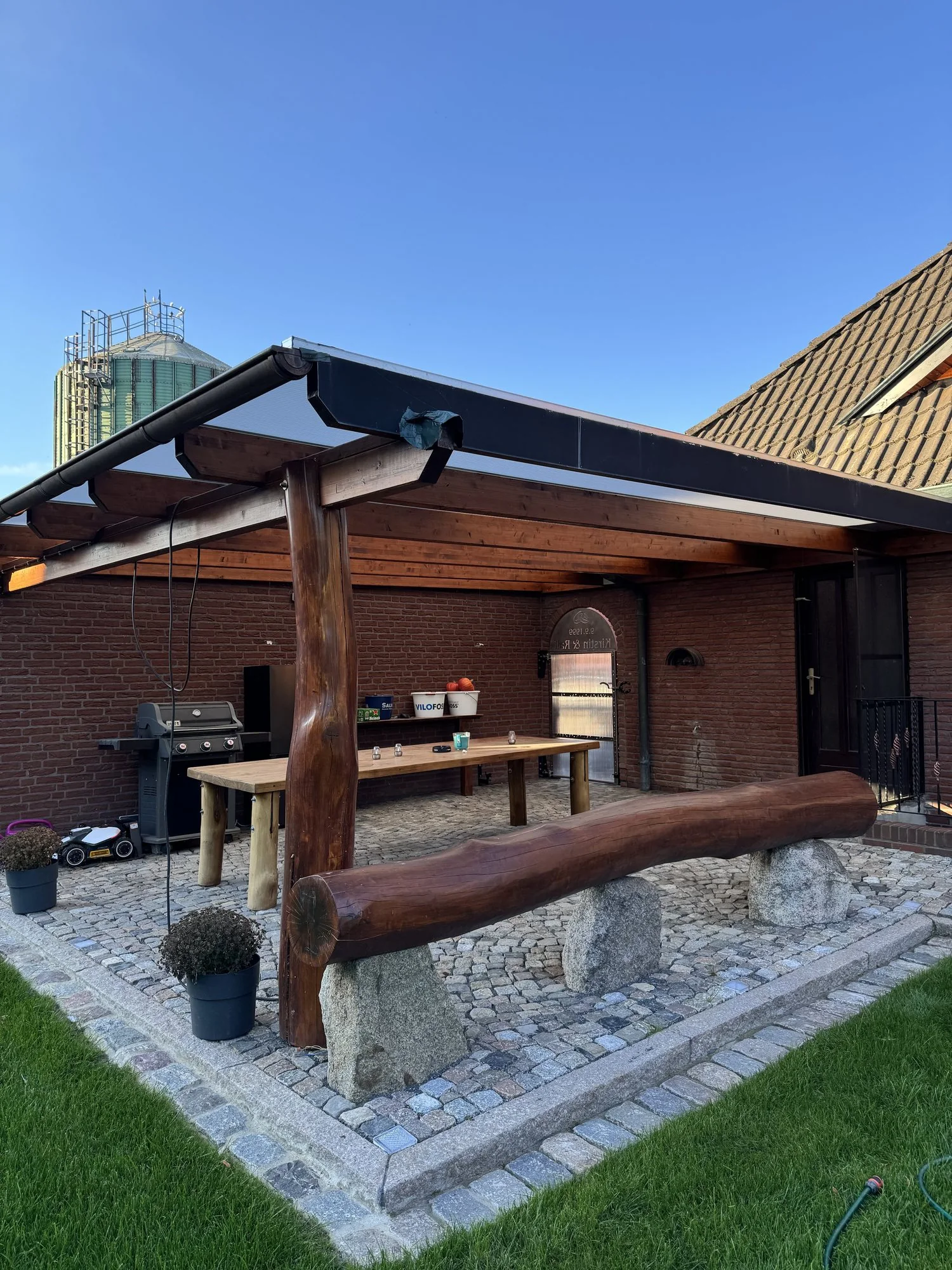 Überdachter Garten-Sitzplatz mit Holzbank und Natursteinpflaster, Seitenansicht