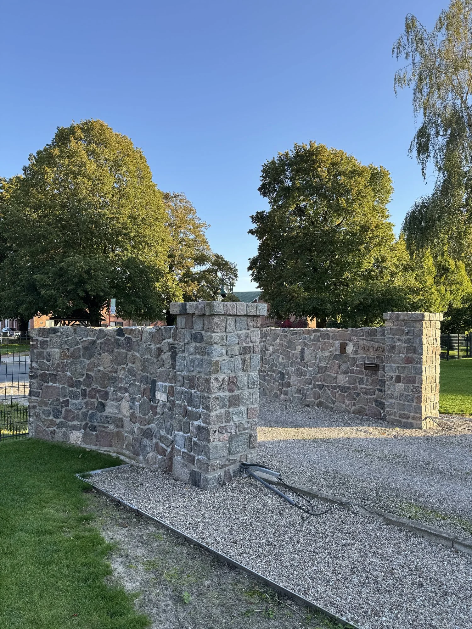 Natursteinmauer mit gemauerten Pfeilern an der Einfahrt