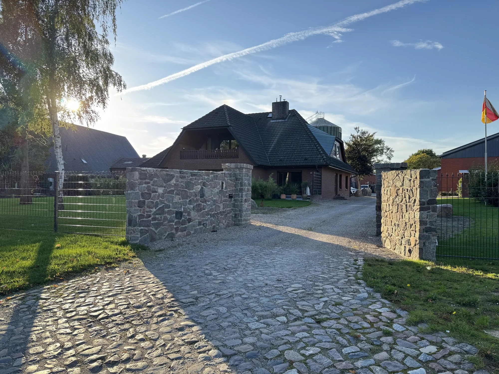 Natursteineinfahrt mit gemauerten Steinpfeilern und Zaun