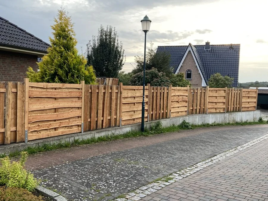 Neuer Holzzaun entlang einer Pflasterfläche